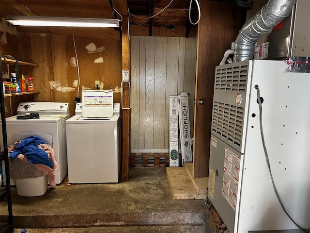 laundry room with heating unit, wooden walls, and separate washer and dryer