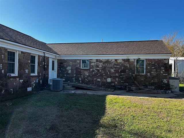 rear view of house with cooling unit and a yard