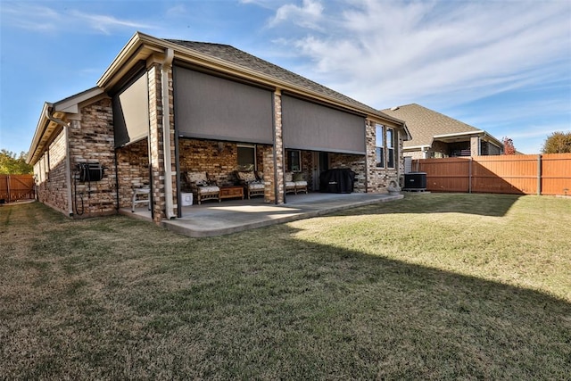 back of property with central AC, a patio area, and a lawn