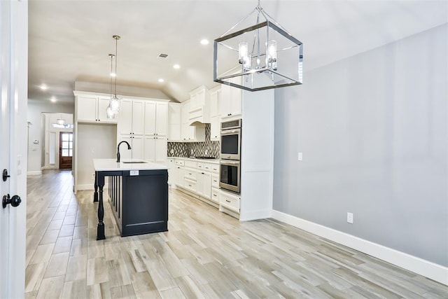 kitchen featuring decorative light fixtures, sink, white cabinets, and decorative backsplash