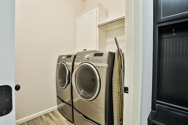 laundry area featuring light hardwood / wood-style flooring, cabinets, and washing machine and clothes dryer