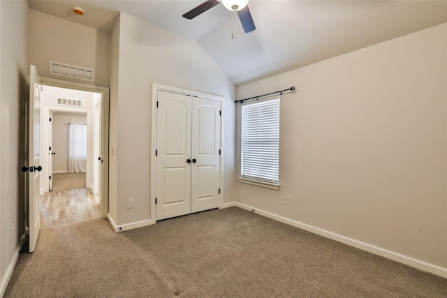 unfurnished bedroom featuring ceiling fan, light colored carpet, vaulted ceiling, and a closet