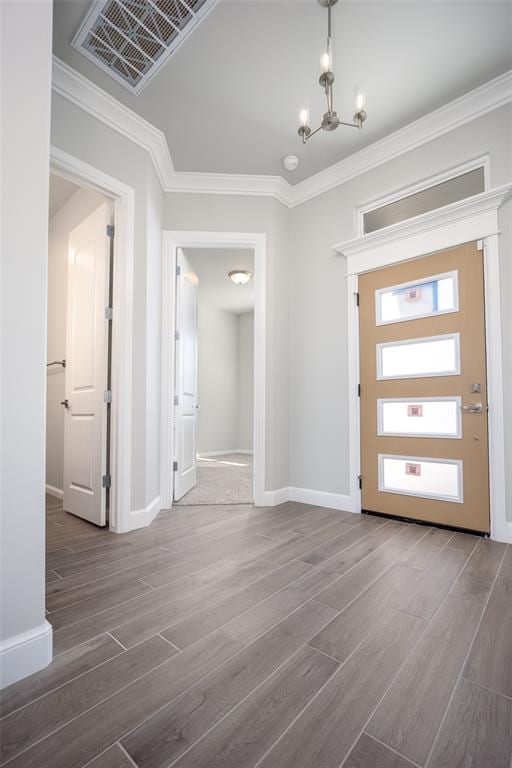 entrance foyer featuring wood-type flooring, crown molding, and an inviting chandelier