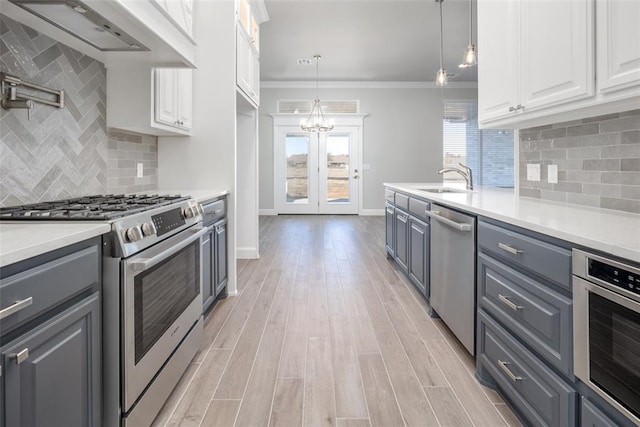 kitchen with appliances with stainless steel finishes, pendant lighting, white cabinetry, and gray cabinetry