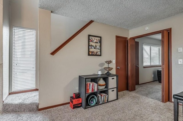 hall with light colored carpet and a textured ceiling