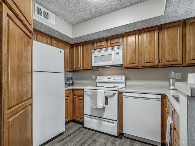 kitchen featuring a textured ceiling, wood-type flooring, and white appliances