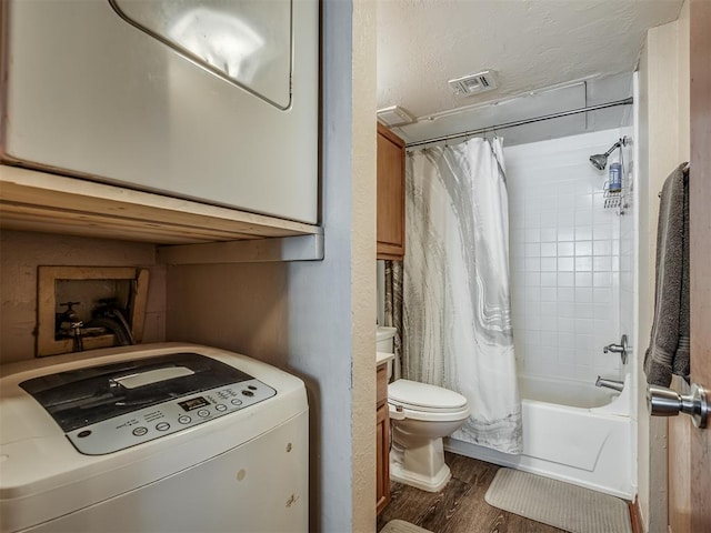 bathroom featuring hardwood / wood-style floors, toilet, shower / bathtub combination with curtain, and washer / clothes dryer