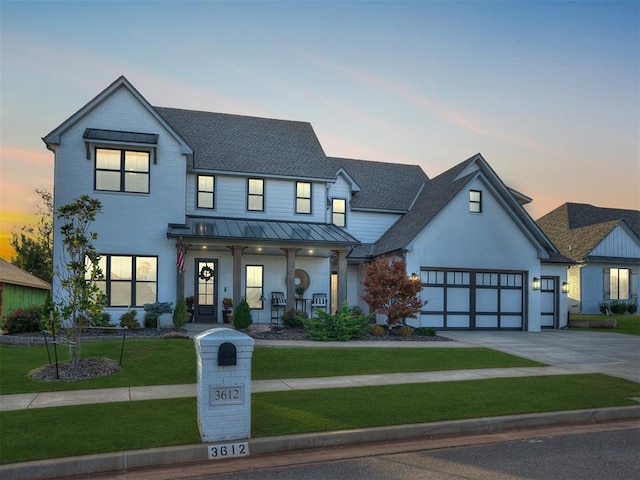 modern farmhouse style home featuring covered porch, a garage, and a lawn