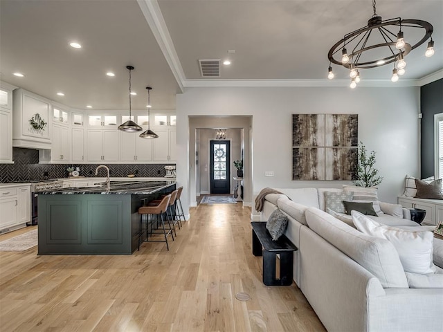 living room with light hardwood / wood-style floors, crown molding, and an inviting chandelier