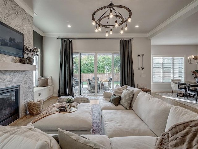 living room featuring a healthy amount of sunlight, a large fireplace, light hardwood / wood-style floors, and a notable chandelier