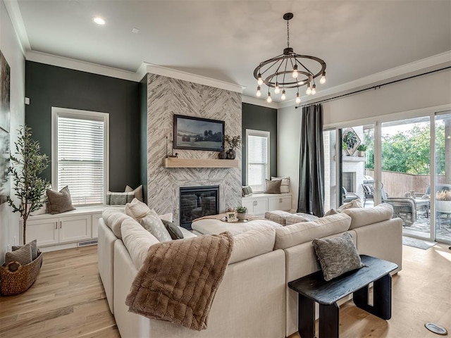 living room with light hardwood / wood-style flooring, a high end fireplace, crown molding, and an inviting chandelier