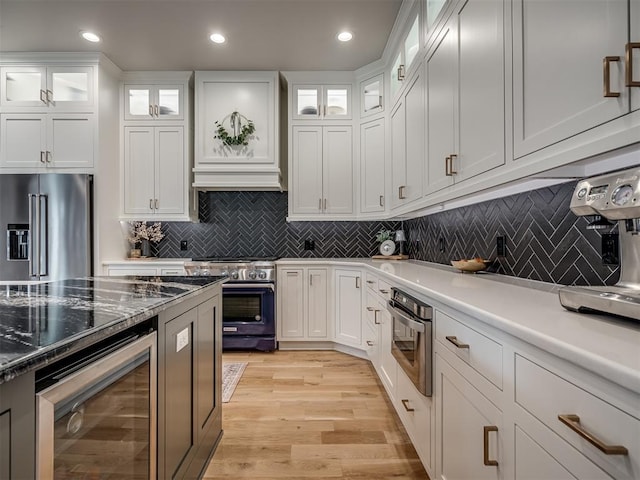 kitchen featuring beverage cooler, white cabinetry, tasteful backsplash, light hardwood / wood-style floors, and high quality appliances