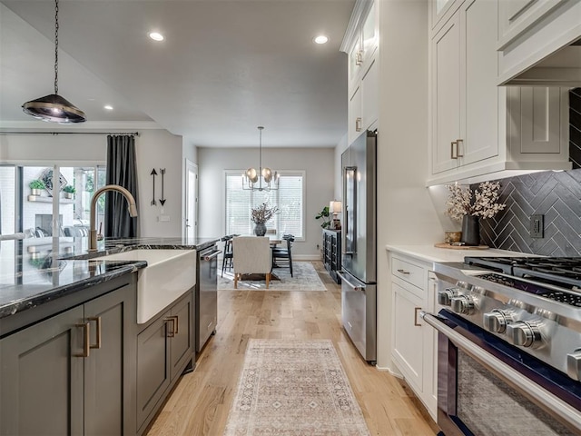 kitchen with decorative light fixtures, white cabinets, decorative backsplash, and appliances with stainless steel finishes