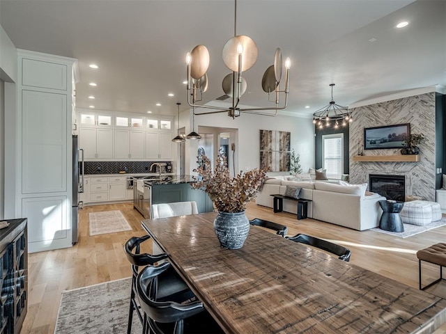 dining space with ceiling fan, a premium fireplace, and light hardwood / wood-style flooring