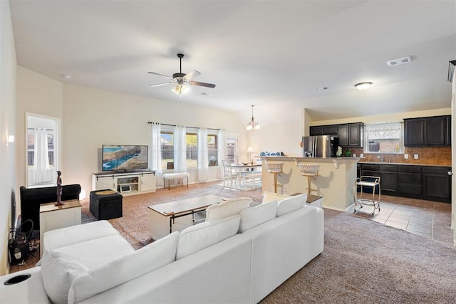 living room featuring light tile patterned floors and ceiling fan with notable chandelier