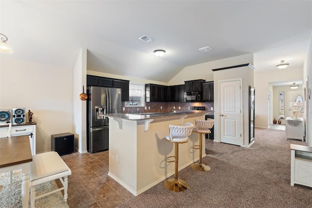 kitchen with backsplash, lofted ceiling, a breakfast bar area, dark carpet, and appliances with stainless steel finishes