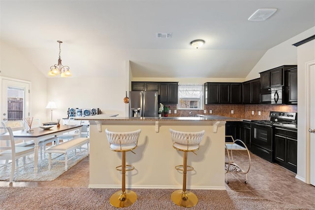 kitchen with a kitchen breakfast bar, an island with sink, vaulted ceiling, light tile patterned floors, and black appliances