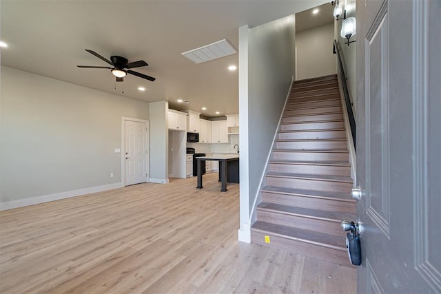 stairway with hardwood / wood-style flooring, ceiling fan, and sink