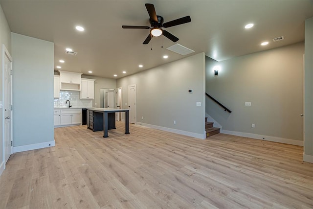 unfurnished living room featuring light wood-type flooring, sink, and ceiling fan