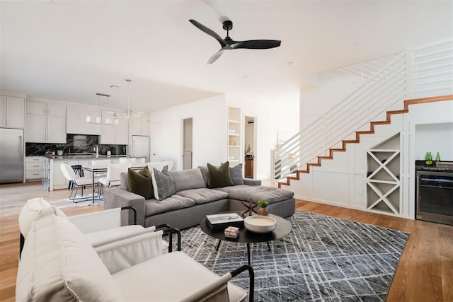 living room featuring wine cooler, built in features, light hardwood / wood-style floors, and ceiling fan