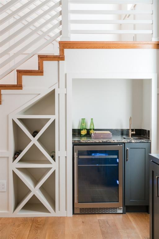 bar featuring beverage cooler and light hardwood / wood-style floors