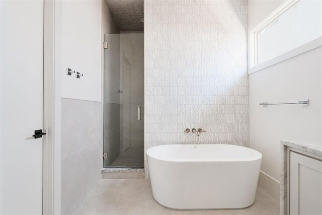 bathroom featuring independent shower and bath, vanity, and tile walls