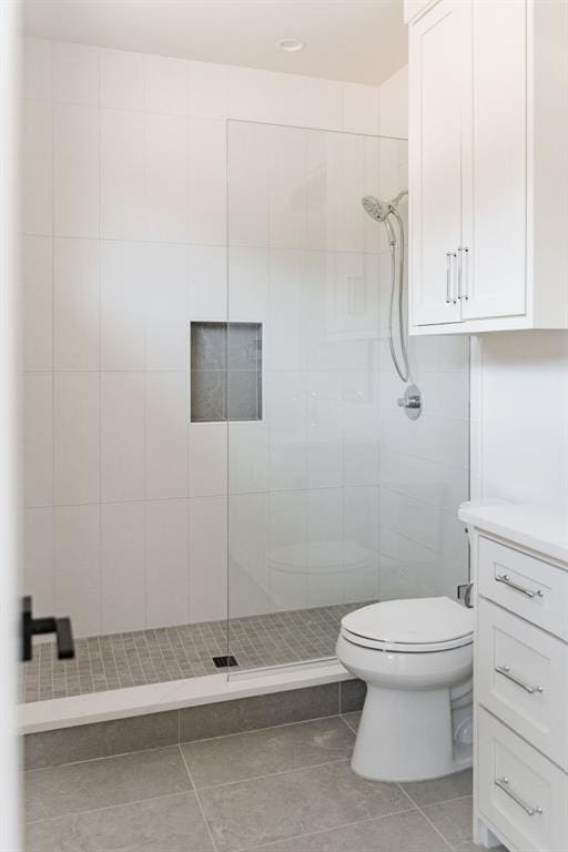 bathroom featuring vanity, tiled shower, tile patterned floors, and toilet