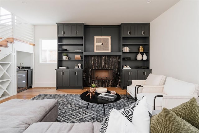 living room with wine cooler, sink, a fireplace, and light hardwood / wood-style floors