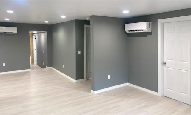 spare room with a wall mounted air conditioner and light wood-type flooring