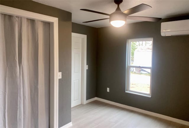 unfurnished bedroom featuring light wood-type flooring, a closet, a wall unit AC, and ceiling fan