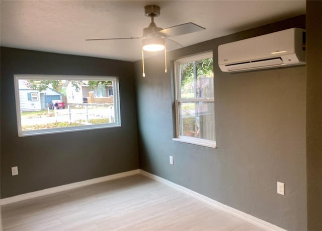 spare room with light hardwood / wood-style floors, a wall unit AC, and ceiling fan