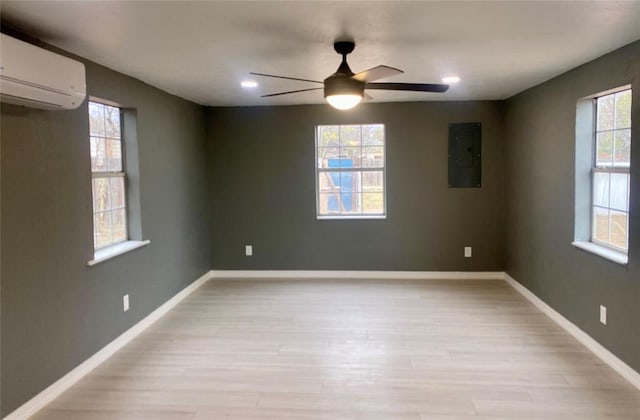 spare room with a wall mounted air conditioner, light hardwood / wood-style floors, and a healthy amount of sunlight