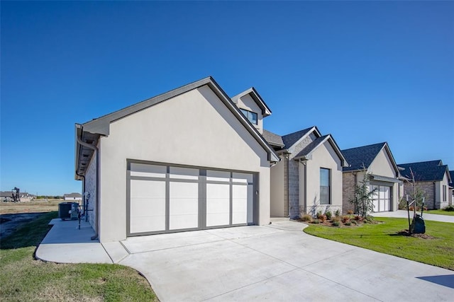 view of front of home with central air condition unit, a front lawn, and a garage