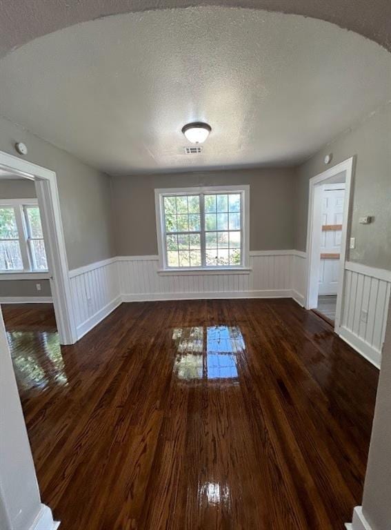 spare room featuring a textured ceiling and dark hardwood / wood-style flooring