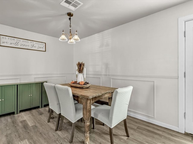 dining space with light hardwood / wood-style floors and a notable chandelier