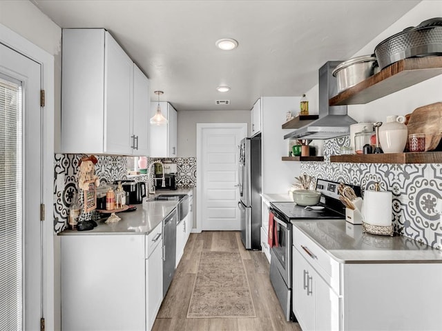 kitchen featuring appliances with stainless steel finishes, exhaust hood, decorative light fixtures, light hardwood / wood-style flooring, and white cabinetry