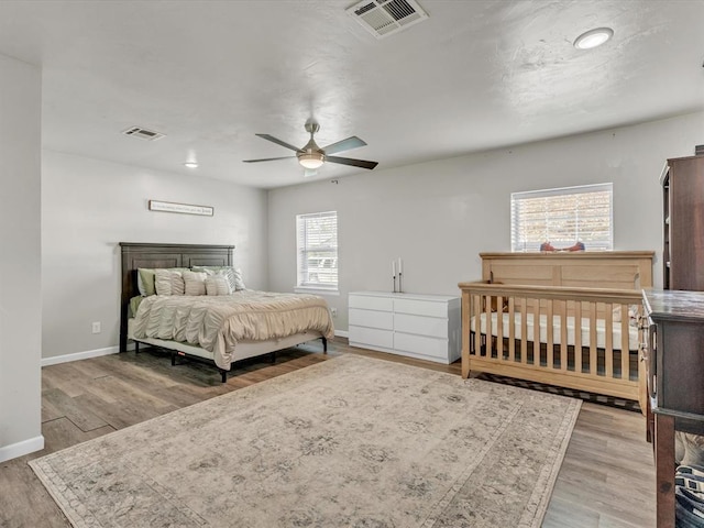 bedroom with multiple windows, ceiling fan, and light hardwood / wood-style flooring