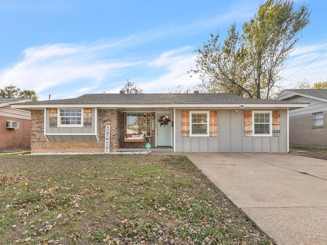 ranch-style house featuring a front yard and a wall mounted AC