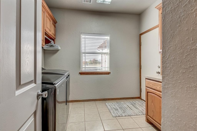 washroom featuring washer and dryer, light tile patterned floors, and cabinets