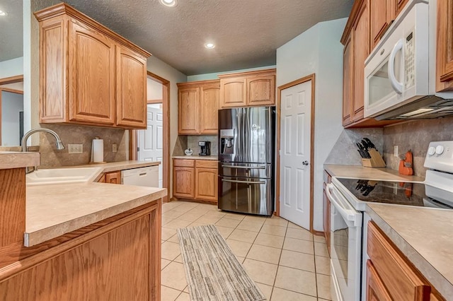 kitchen featuring decorative backsplash, a textured ceiling, white appliances, and sink