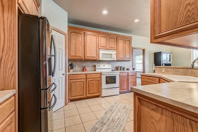 kitchen featuring white appliances, sink, a textured ceiling, tasteful backsplash, and light tile patterned flooring