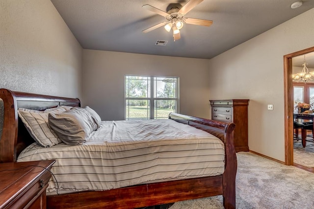 bedroom featuring multiple windows, light colored carpet, and ceiling fan with notable chandelier