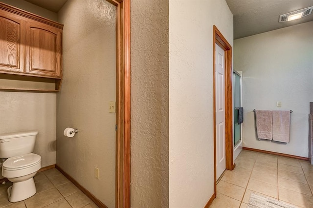 bathroom featuring toilet, tile patterned flooring, and walk in shower