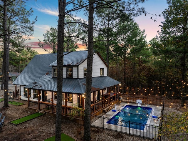 back house at dusk featuring a patio, a pool side deck, and pool water feature