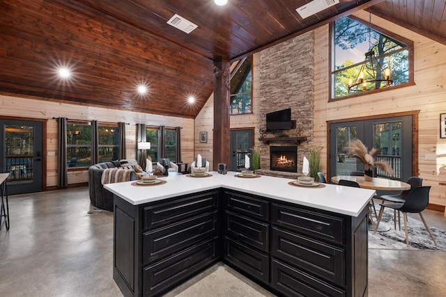 kitchen with high vaulted ceiling, wooden walls, concrete flooring, and wooden ceiling