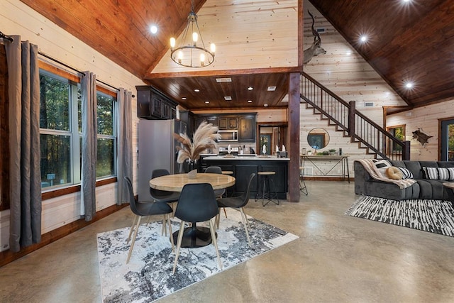 dining space featuring high vaulted ceiling, wooden ceiling, a chandelier, and wood walls