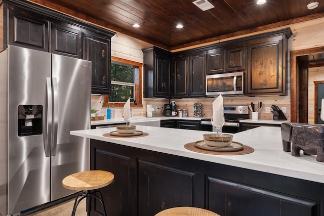 kitchen with wooden walls, sink, a breakfast bar area, stainless steel appliances, and wooden ceiling