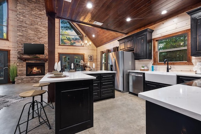 kitchen with a kitchen island, wood walls, a kitchen breakfast bar, stainless steel appliances, and wooden ceiling