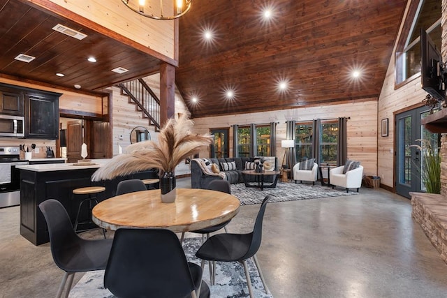 dining room featuring wood ceiling, wooden walls, high vaulted ceiling, and concrete floors