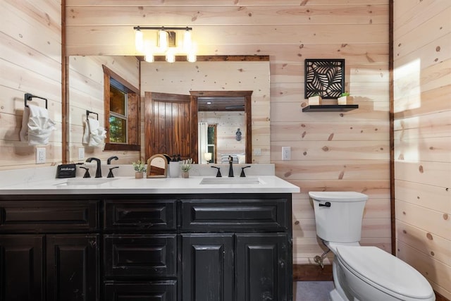 bathroom with vanity, wood walls, and toilet